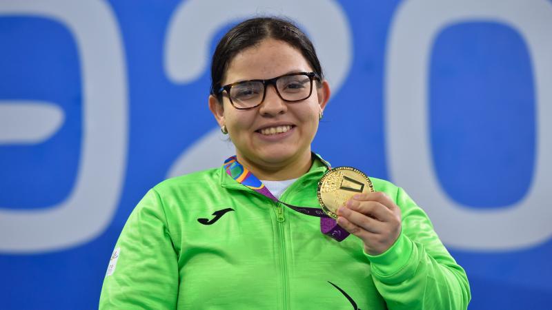 a female Para swimmer holding up her gold medal