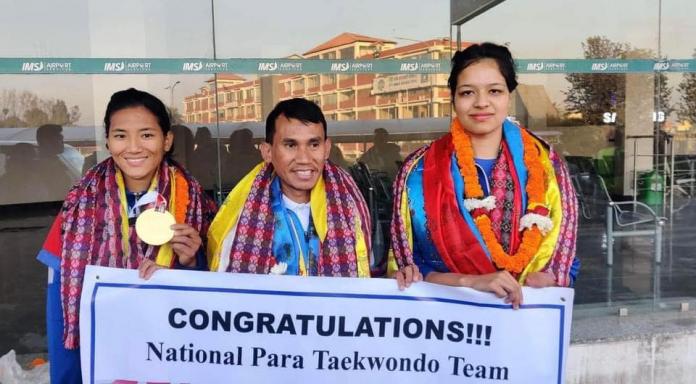 Two athletes and a coach stand with traditional decorations around their necks while holding a sign that reads "Congratulations! National Para Taekwondo Team".