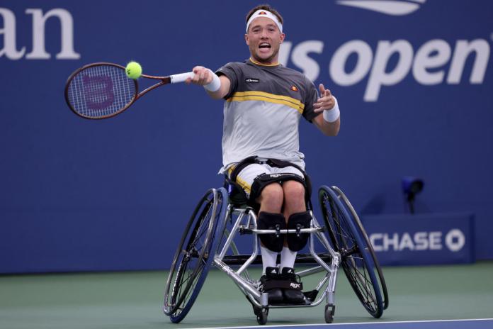 A male wheelchair tennis player hits the ball 