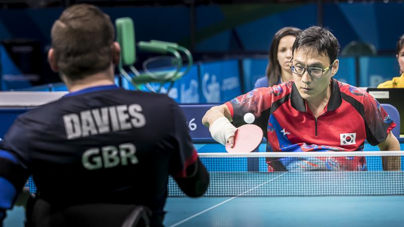 Two men in wheelchairs competing in table tennis