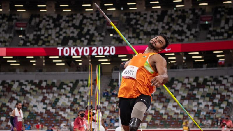 A male athlete with a prosthetic leg steps forward to throw a javelin