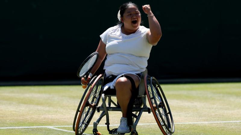 A female wheelchair tennis player is pumping her fist