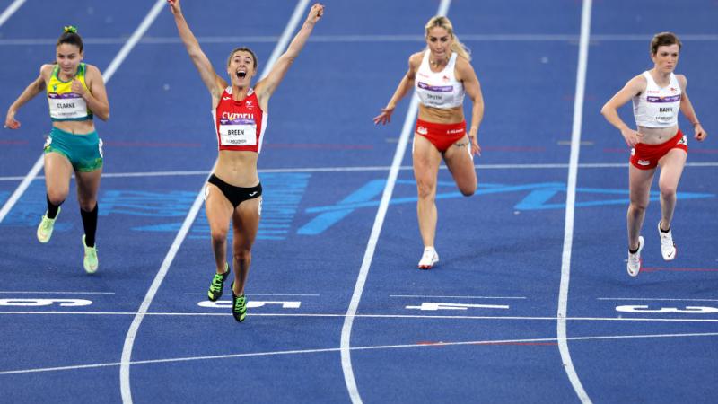 A woman crossing the line ahead of three other women in an athletics track