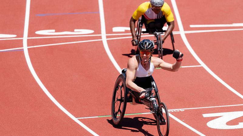 A female wheelchair racer celebrating with another racer behind her