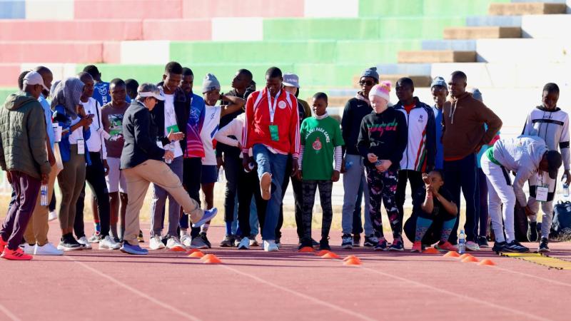 About 25 athletes gather on a track during a training camp