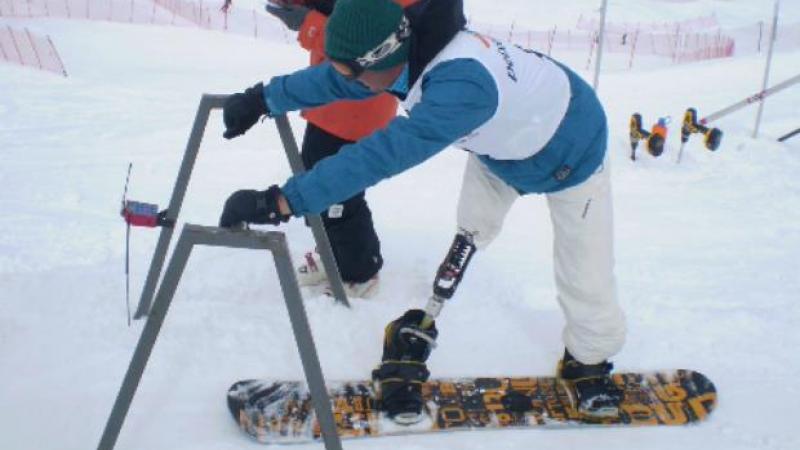 A picture of a man with a prosthesis practising snowboard
