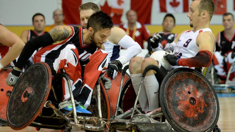 Two wheelchair rugby players tackeling each other