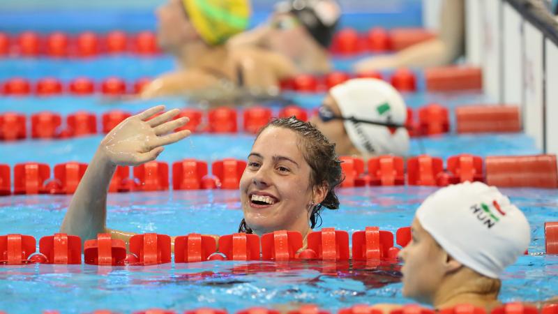 female Para swimmer Aurelie Rivard takes her swimming cap off and celebrates in the pool after winning a race