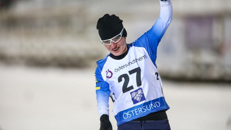 female Para biahthlete Oleksandra Kononova raises her fist in triumph as she crosses the finish line