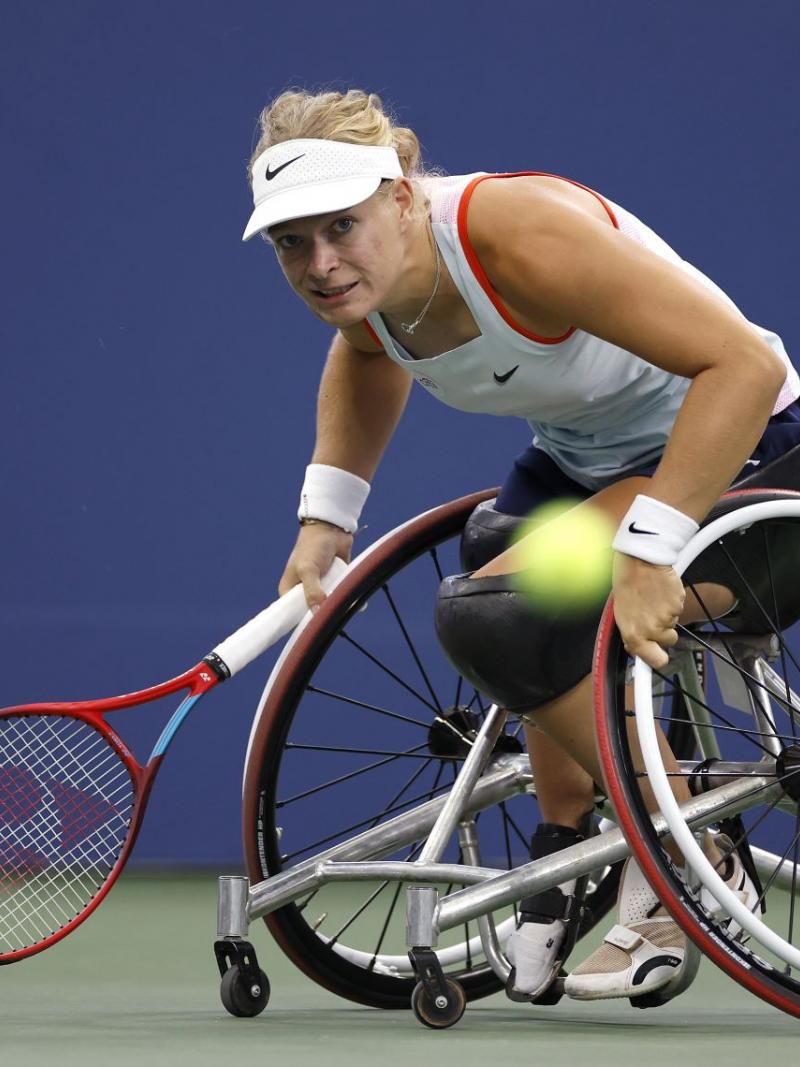 A female wheelchair tennis player hits a ball during ca game.