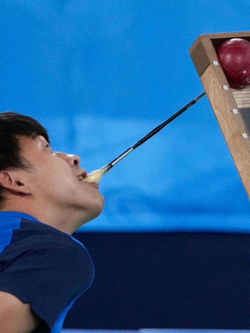 A Korean boccia player uses a a pointer with his mouth to position the ball on the ramp