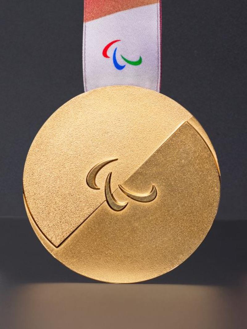 Photo of silver, gold and bronze medals - the medals have the Agitos symbol in the centre and have red ribbons