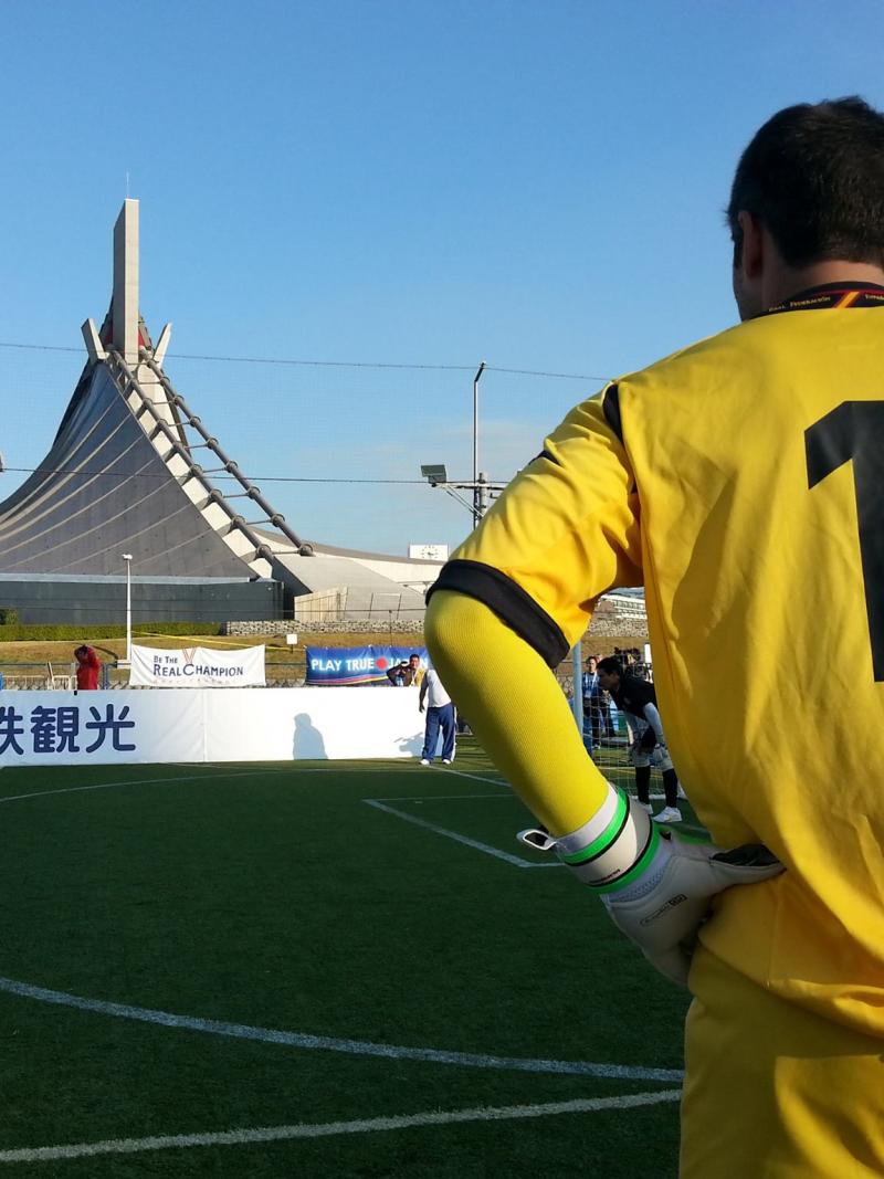 Back of a football player looking at another blindfolded player who prepares to shoot a penalty