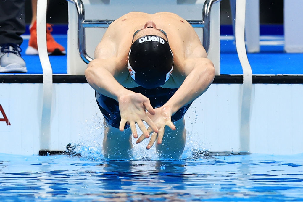 A male swimmer in the starting block in a backstroke race
