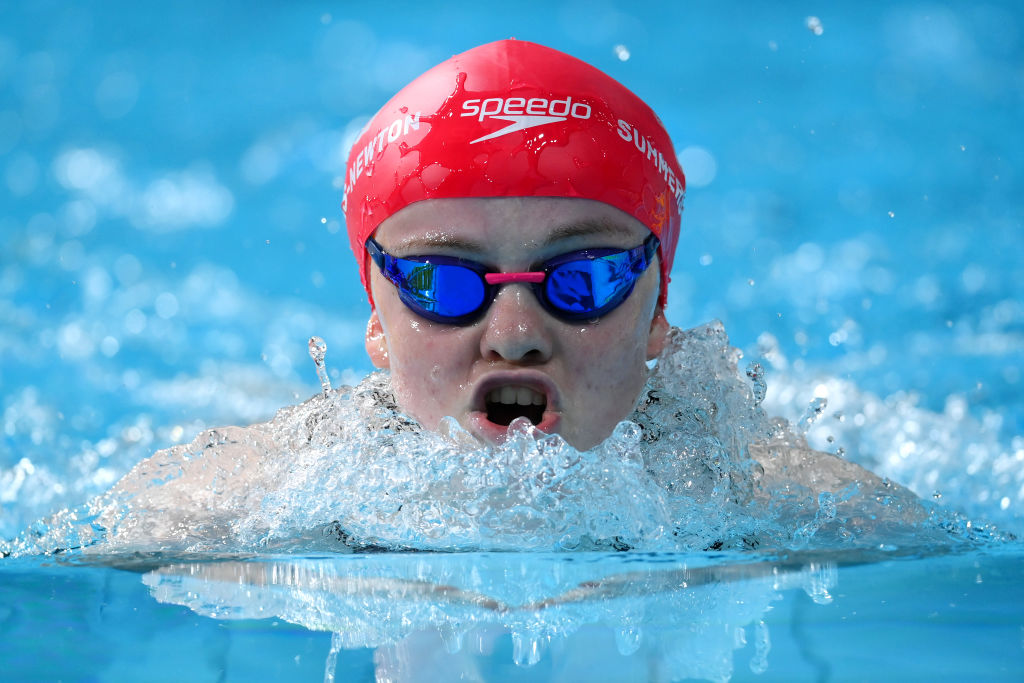 A close up of a female swimmer as she comes up for a breath during a breaststroke race.