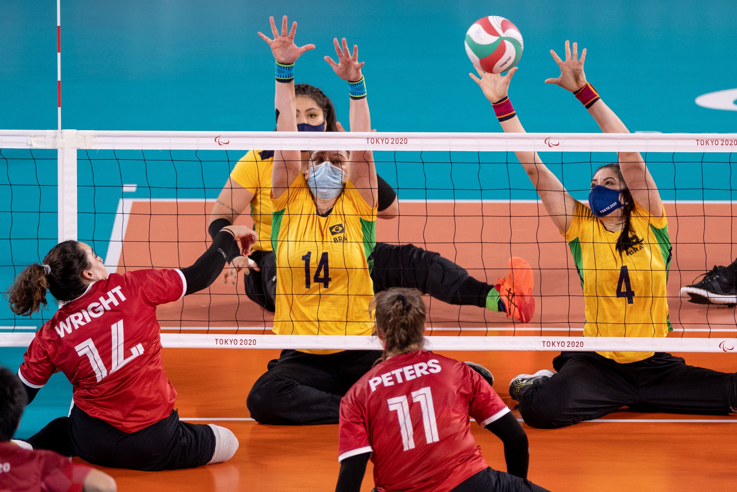 A female sitting volleyball player from Brazil plays the ball during a match against Canada.