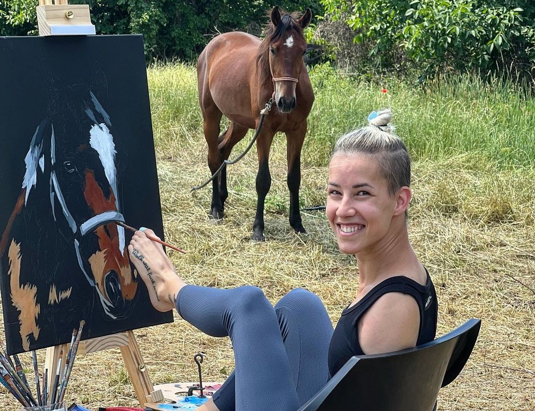 A female paints a picture of a horse with her left foot. 