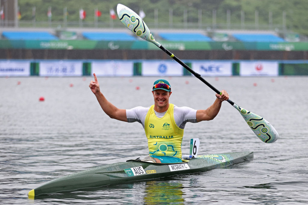 Male Para canoeist Curtis McGrath raises his arms in celebration