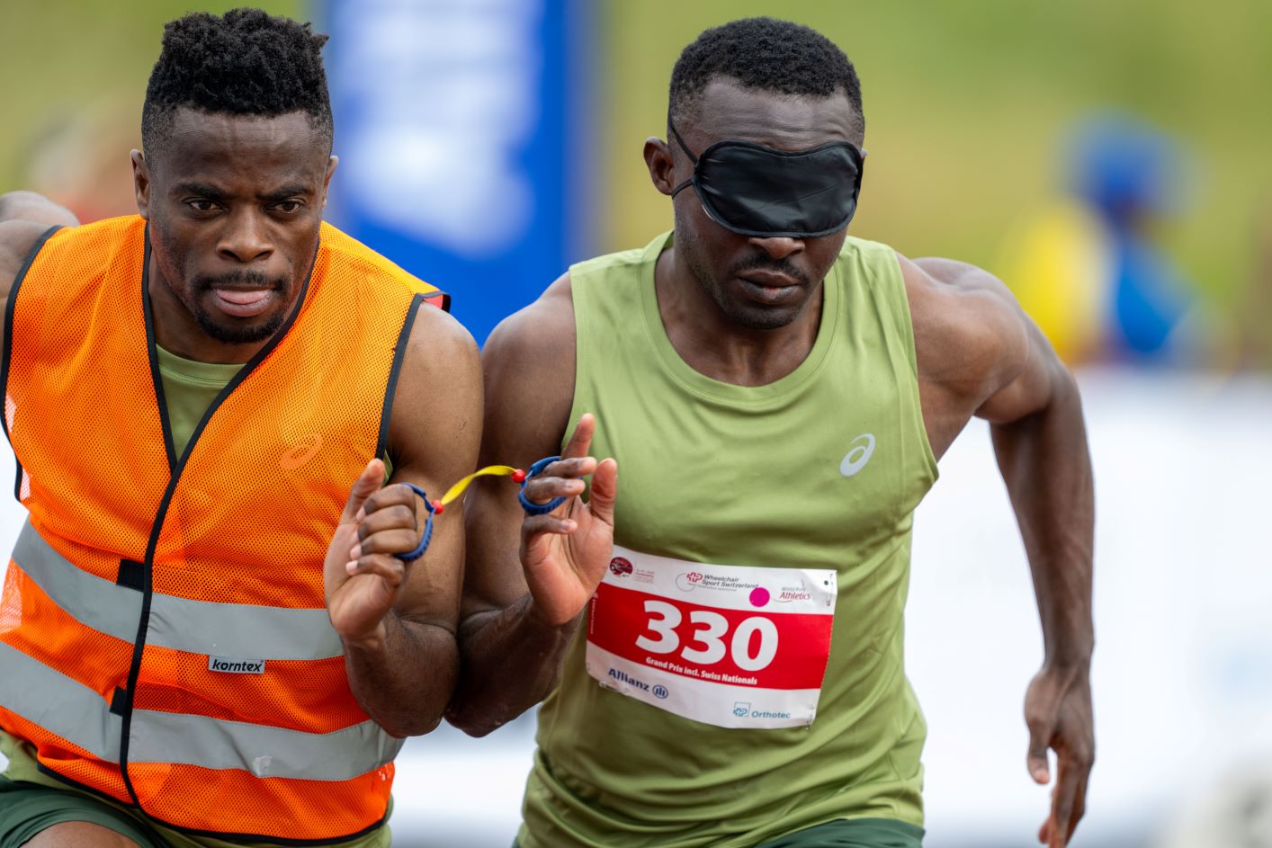 A male sprinter and his sighted guide runner competing.