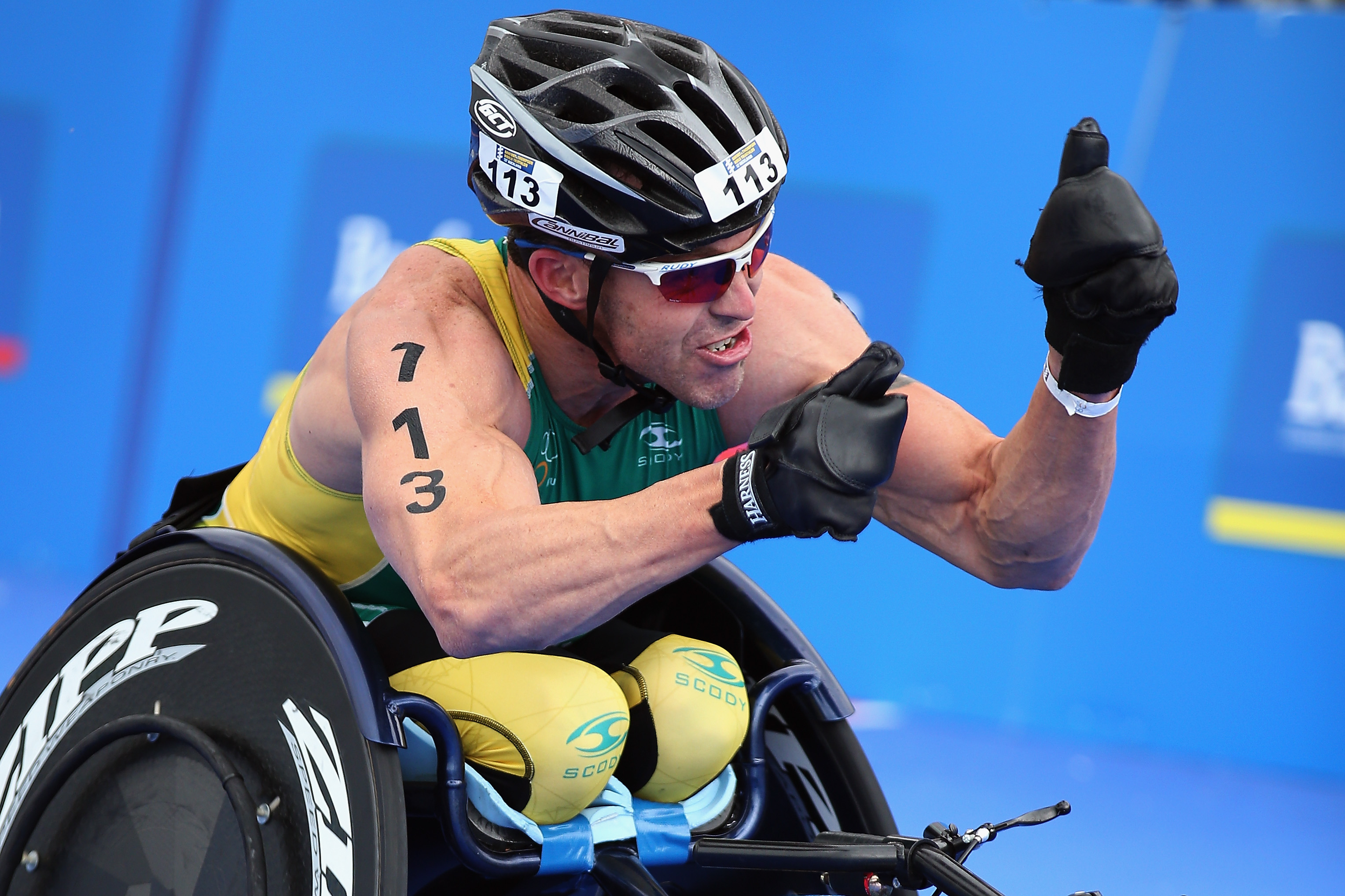 A picture of a man in a wheelchair celebrating his victory after a para-triathlon