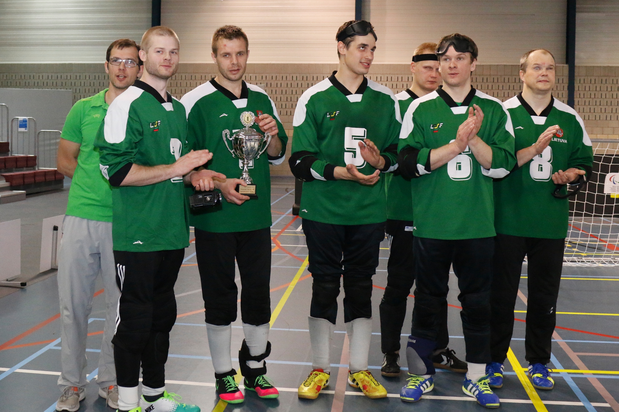 A goalball team faces the camera with their tournament trophy.
