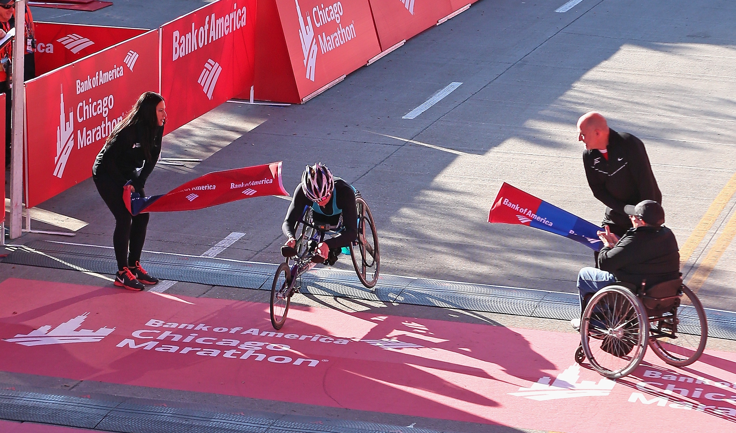 Women in racing wheelchair crossing a finish line