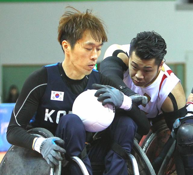 Two men in wheelchairs playing rugby, fighting for the ball