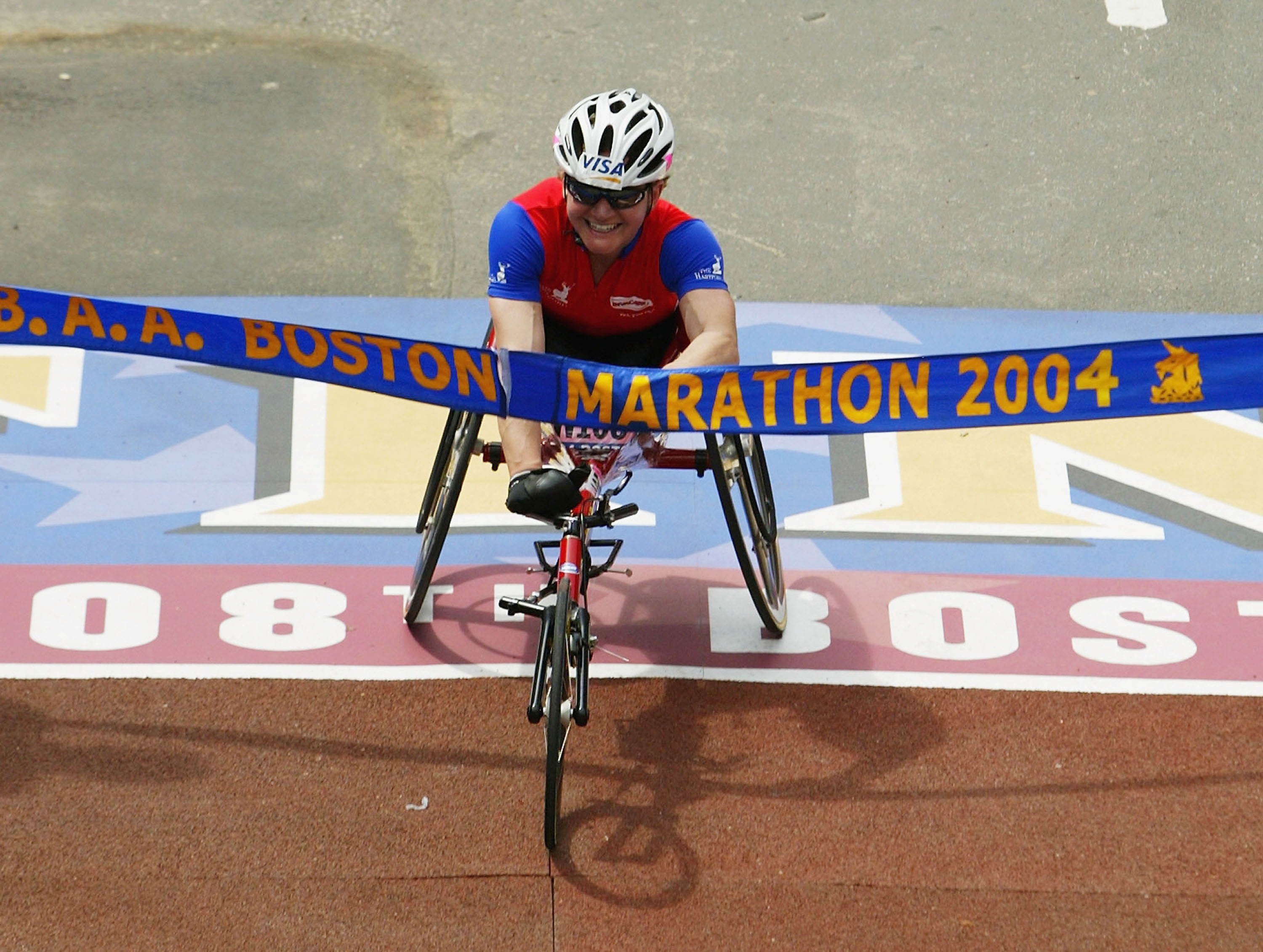 Women in racing wheelchair crosses a finish line