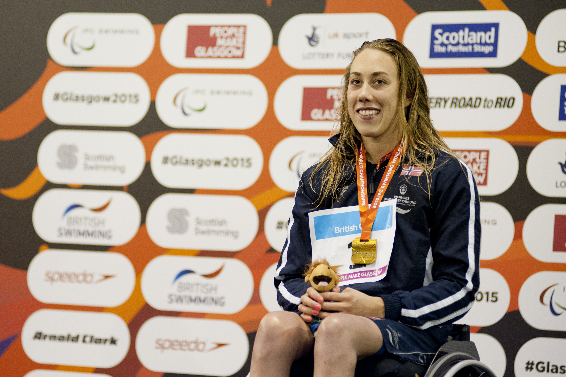 Woman in a wheelchair, on a podium with medal around her neck