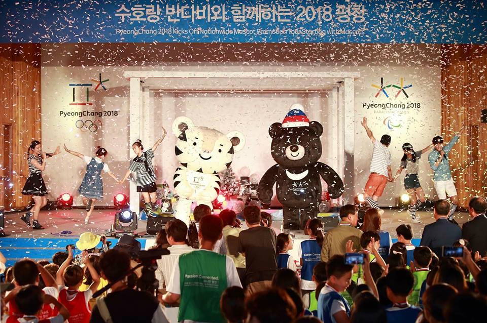 The PyeongChang 2018 full-sized mascots appear on stage in front of a crowd.