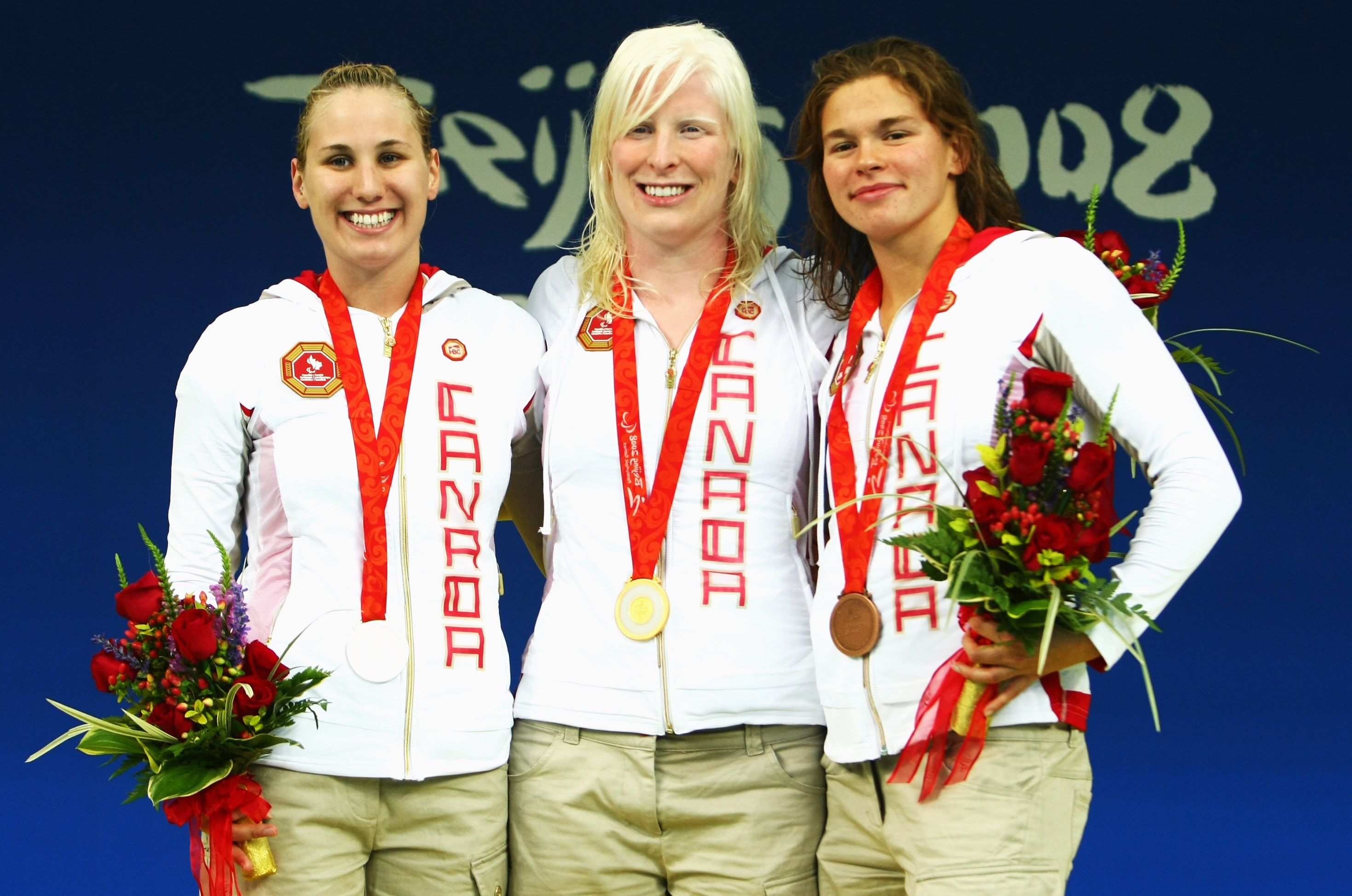 Three female swimmers pose for a photo
