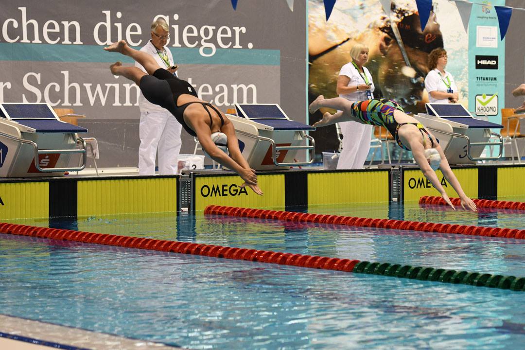 two female swimmers jump into the pool at the start of a race