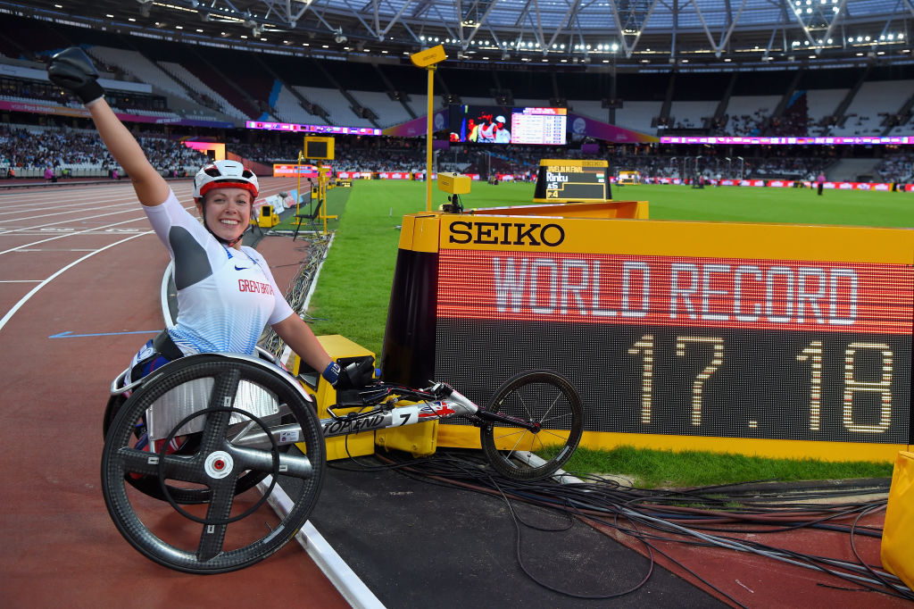 Woman in racing wheelchair next to a screen