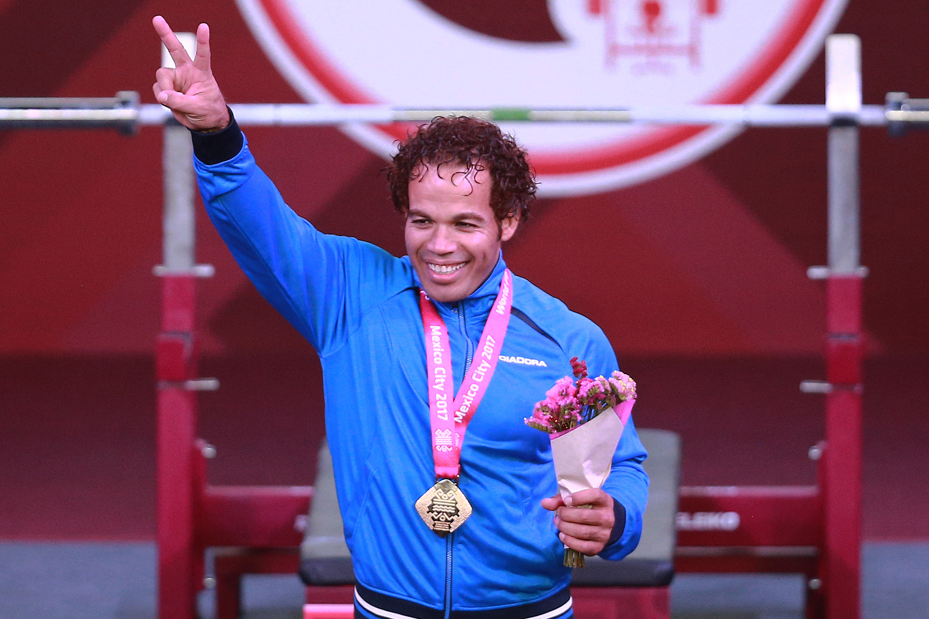 a male powerlifter celebrates his gold medal on the podium