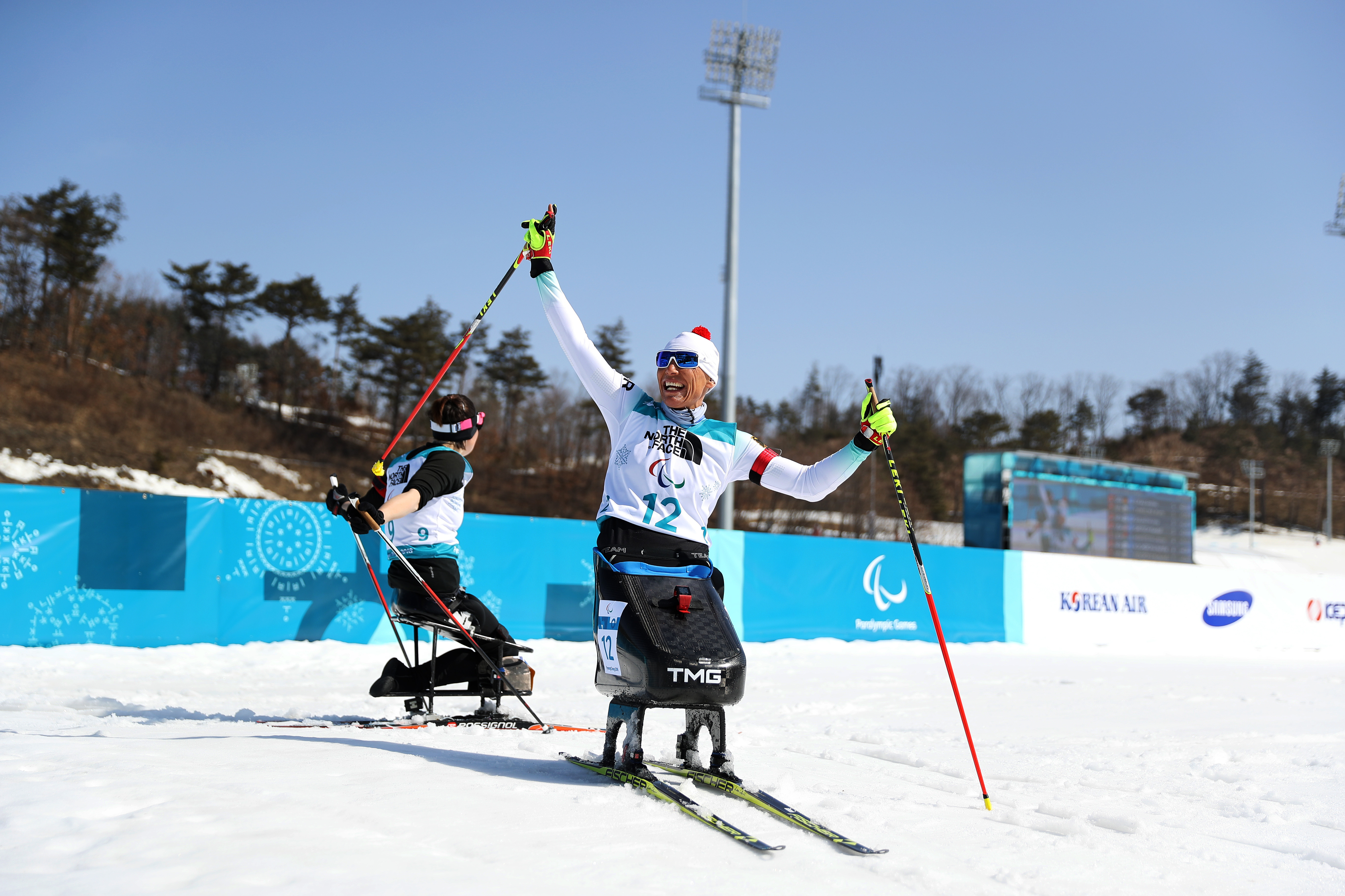 a female Nordic sit skier celebrates on the finish line