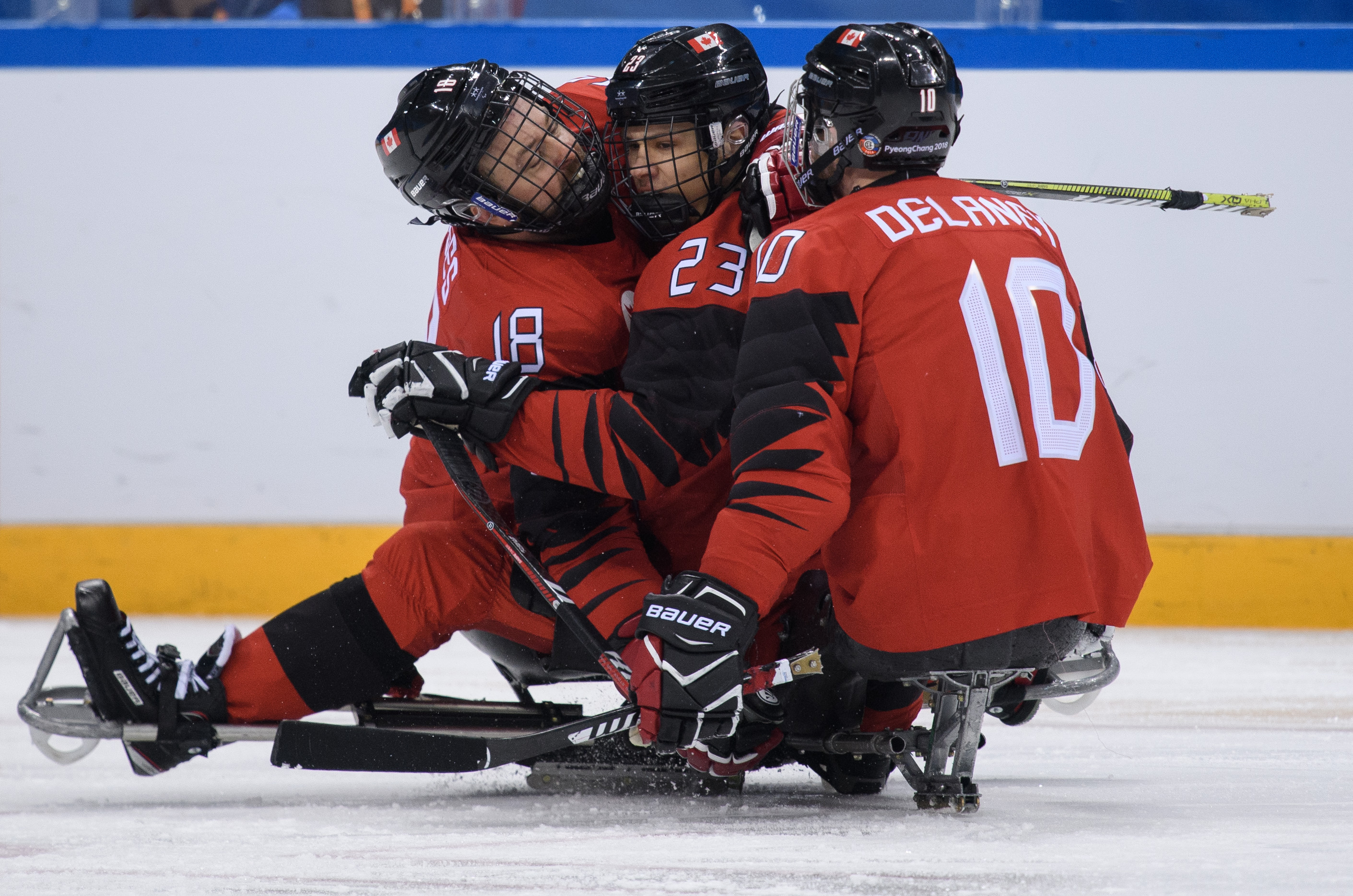 Three Para ice hockey players celebrating a goal