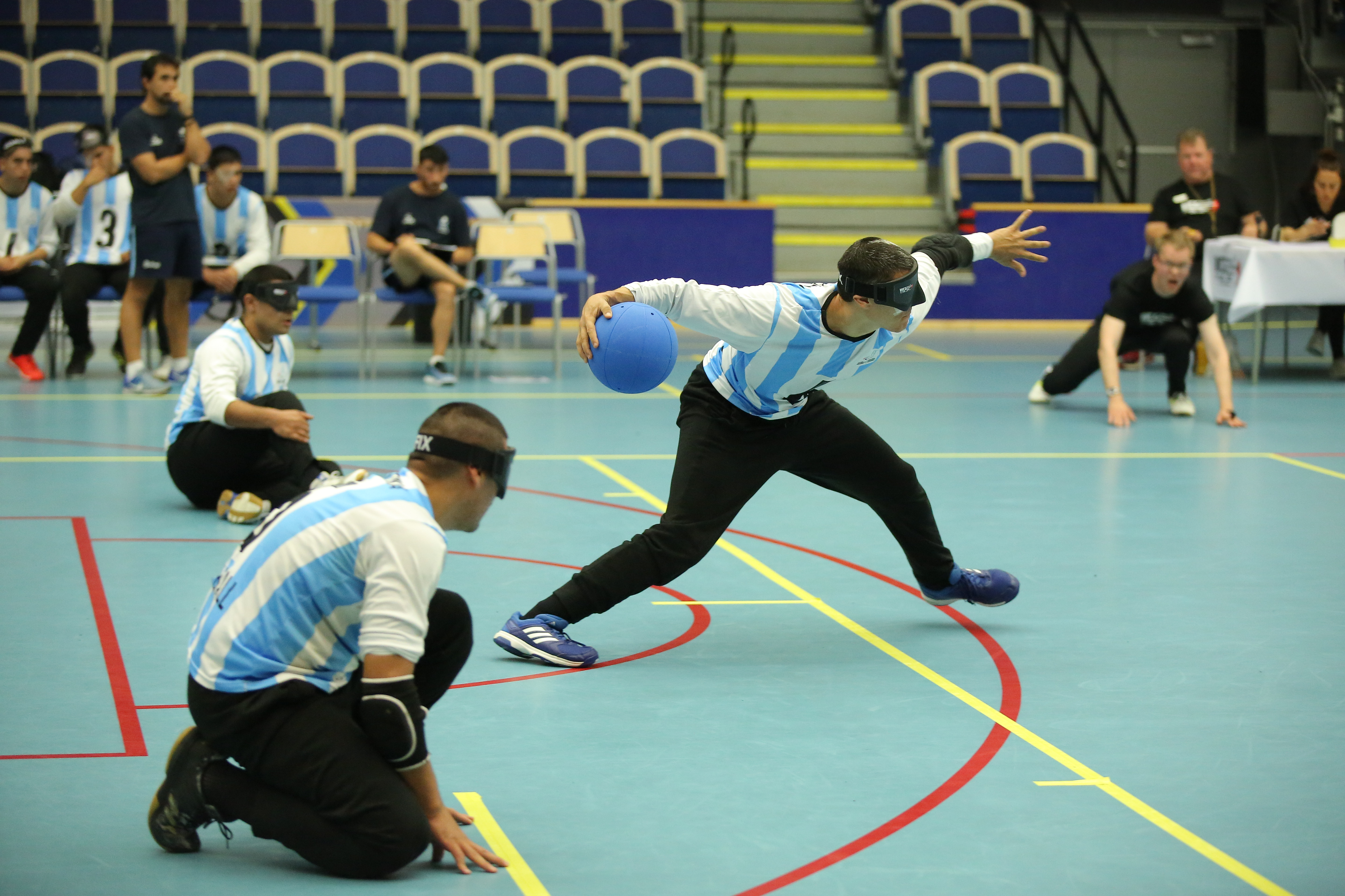 a male goalball player prepares to take a shot while two others wait beside him