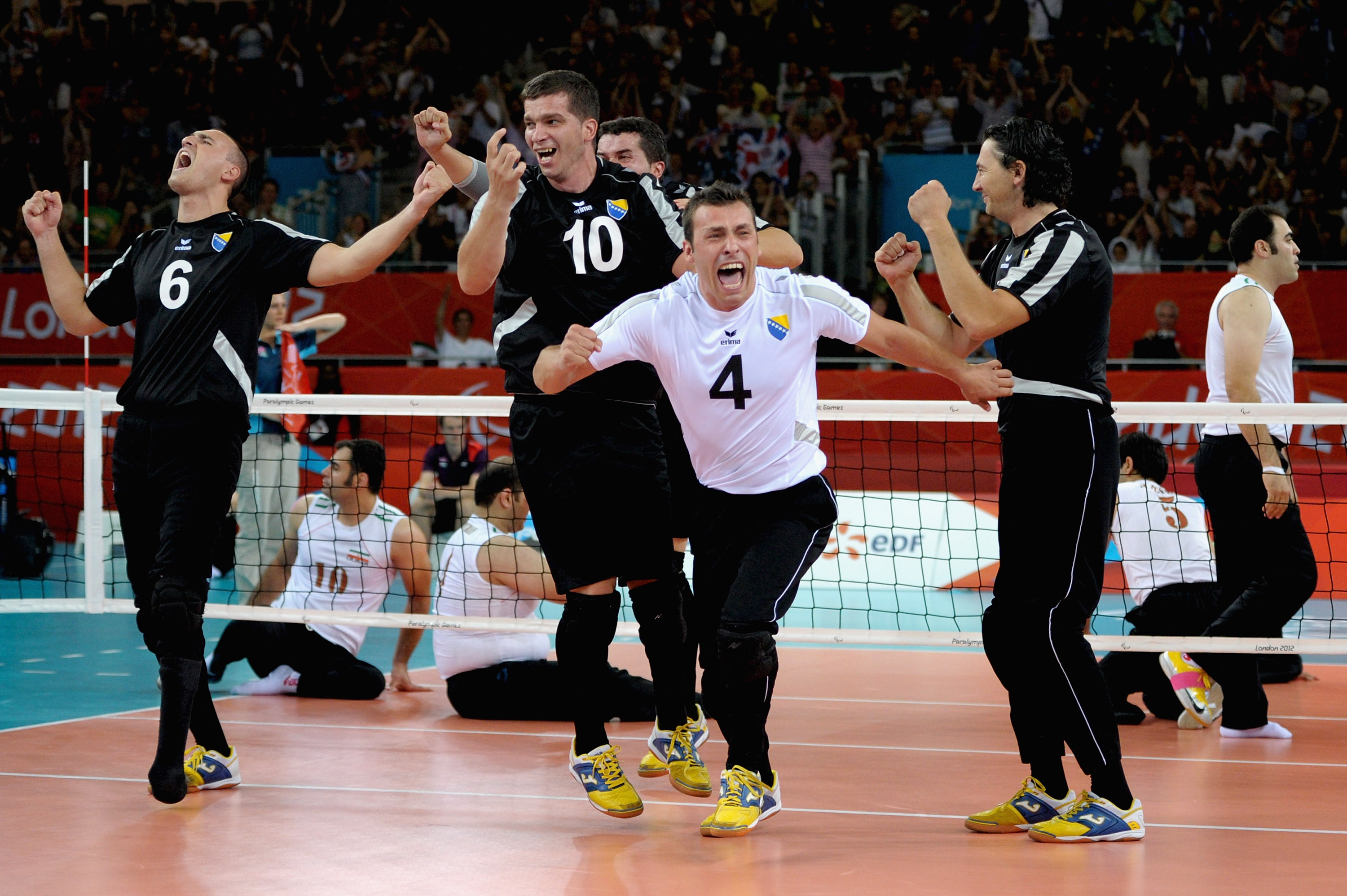 a group of male sitting volleyballers celebrate on the court