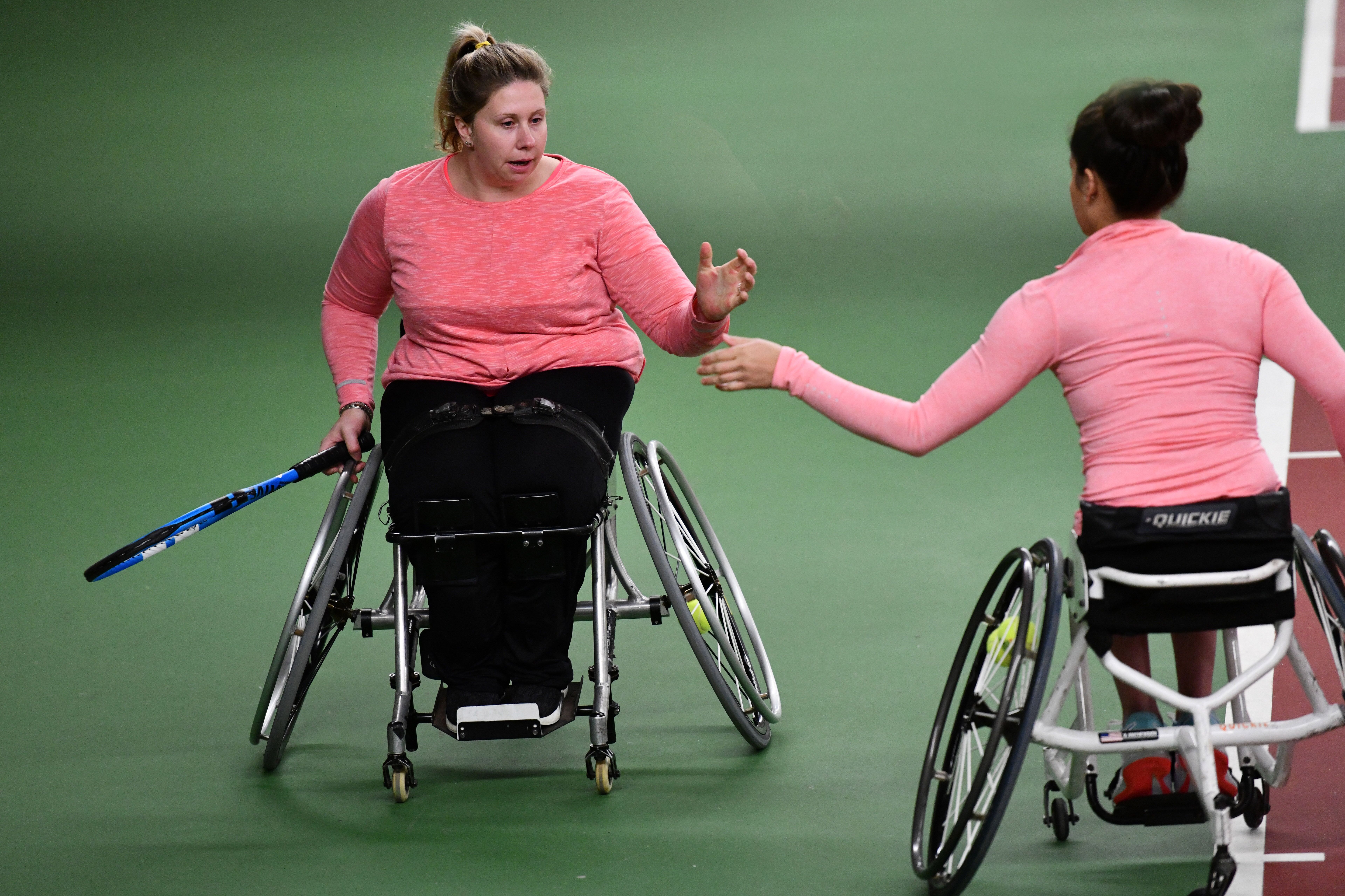 female wheelchair tennis players Louise Hunt and Dana Mathewson high five on the court