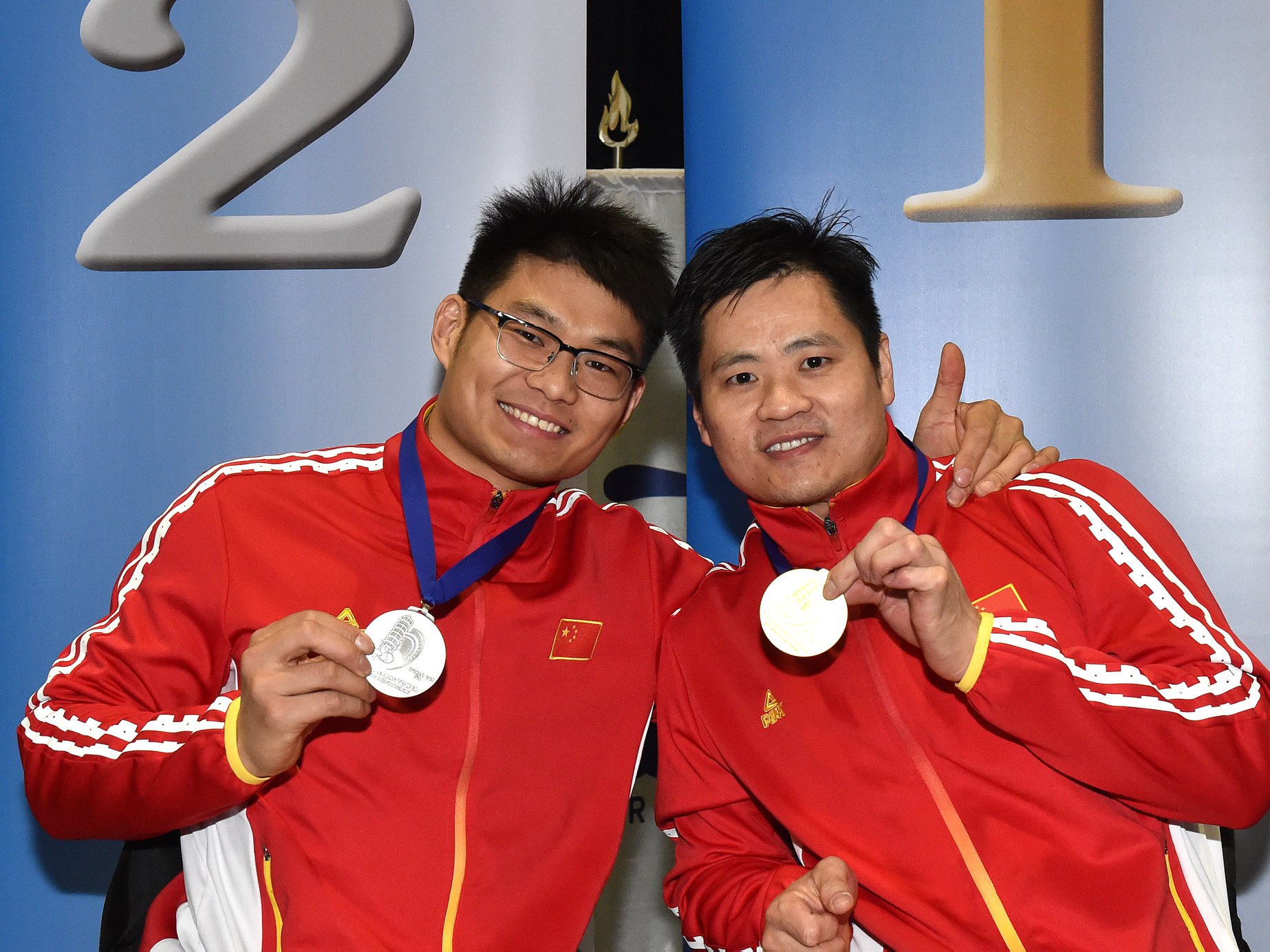 male wheelchair fencers Hu Daoliang and Feng Yanke hold up their medals and smile