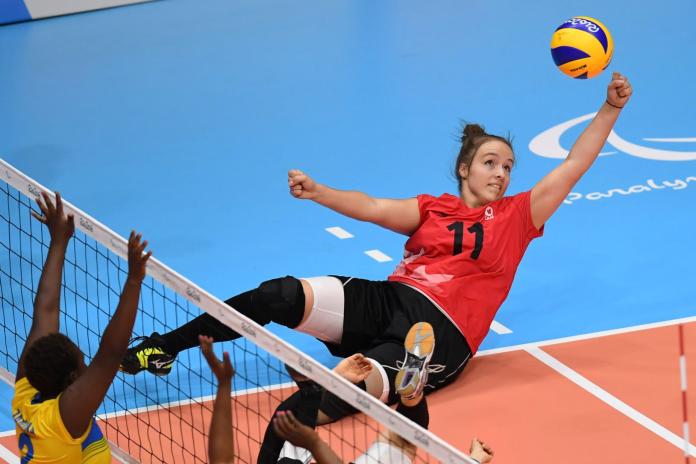 A female sitting volleyball athlete returns the ball during competition