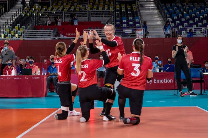 Female sitting volleyball athletes high fives on the court