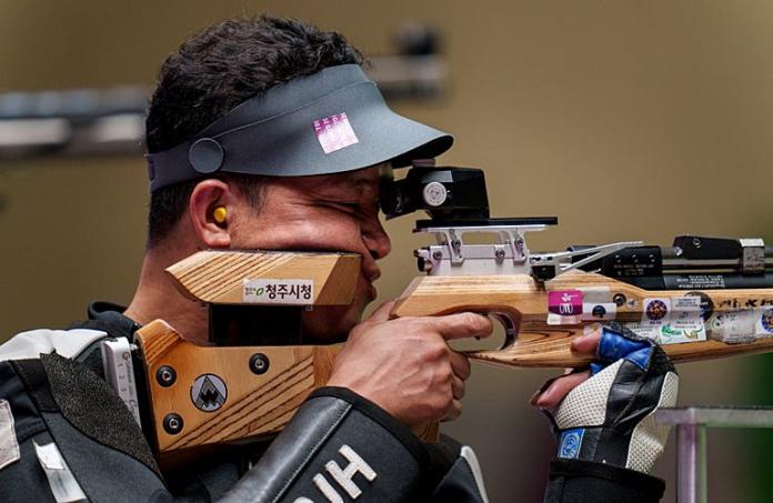 A male shooting Para sport athlete aims for a target