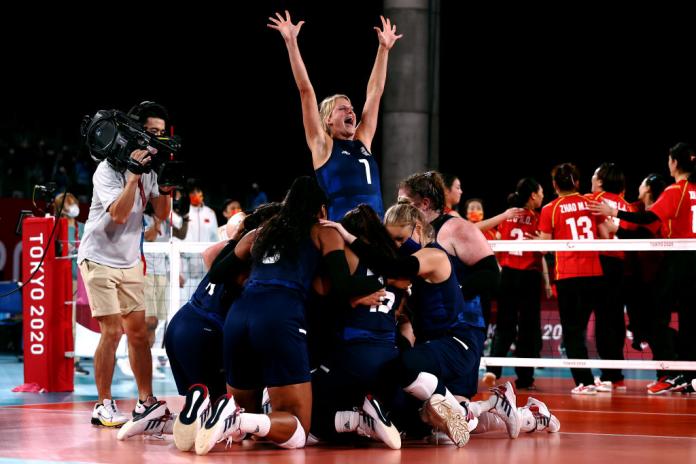 The female sitting volleyball players gather and celebrate on court at the Tokyo 2020 Paralympics