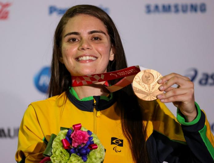 A female Para taekwondo athlete poses for a photo with a bronze medal