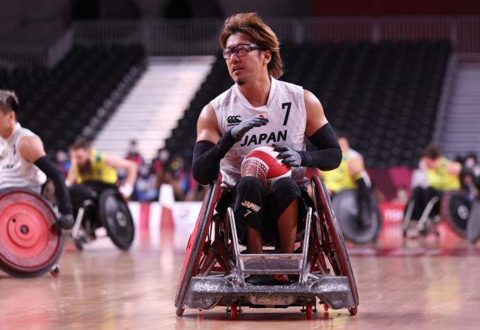A male wheelchair rugby player carries the ball during competition