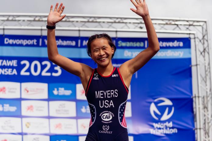 A female Para triathlete raises her arms