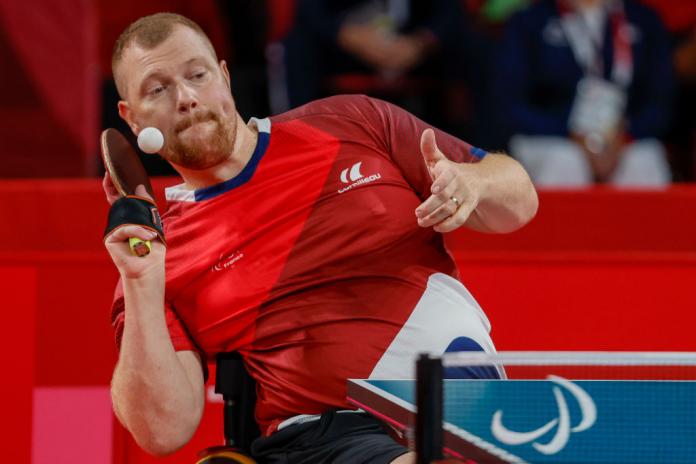 A male Para table tennis player is prepares to return the ball during a match.