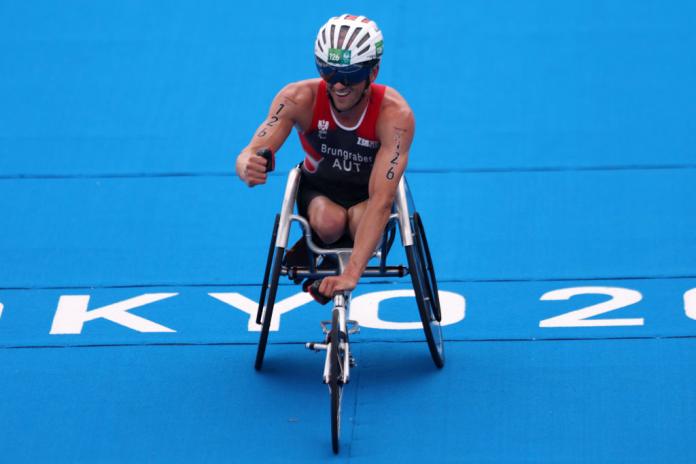 A male triathlete who competes in a wheelchair celebrates