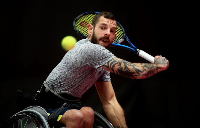A male wheelchair tennis player is about to return the ball